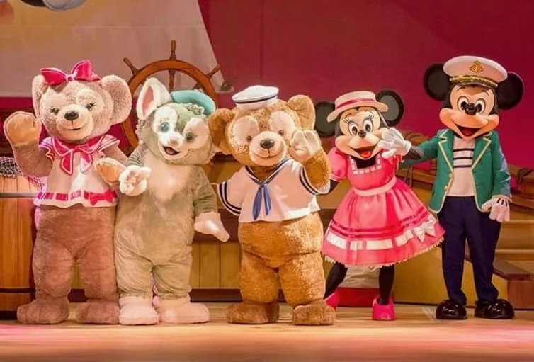 무대에서 인사하는 미키마우스와 디즈니 캐릭터 인형들