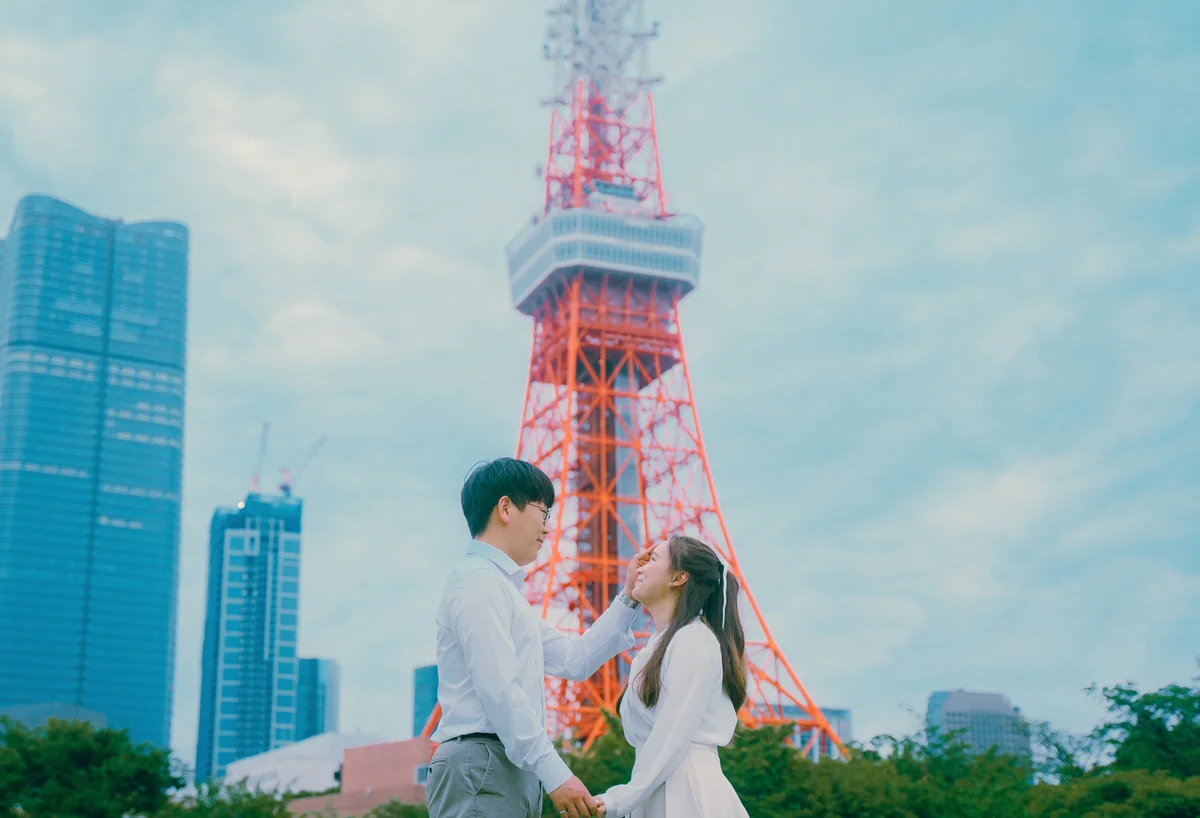 붉은색 도쿄 타워 앞에서 손을 잡고 마주 본 남녀의 모습