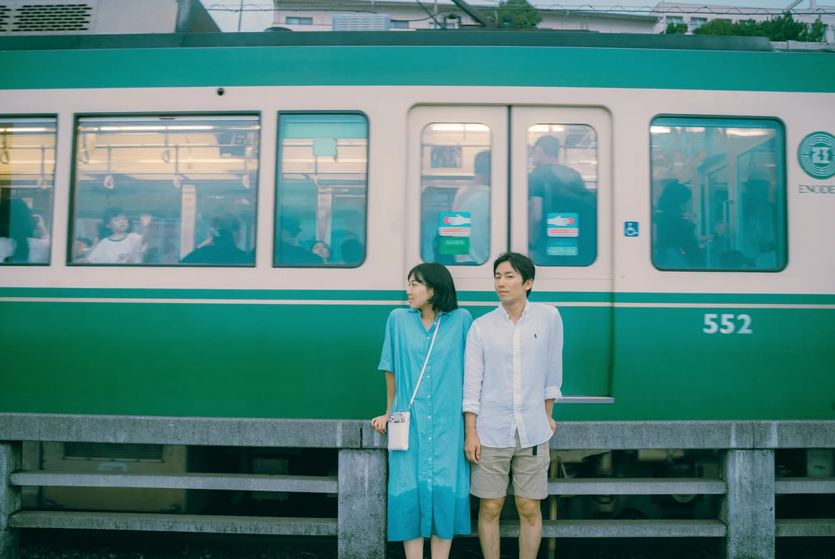 초록색 노면 전차를 배경으로 선 남녀의 감성적인 야외 스냅